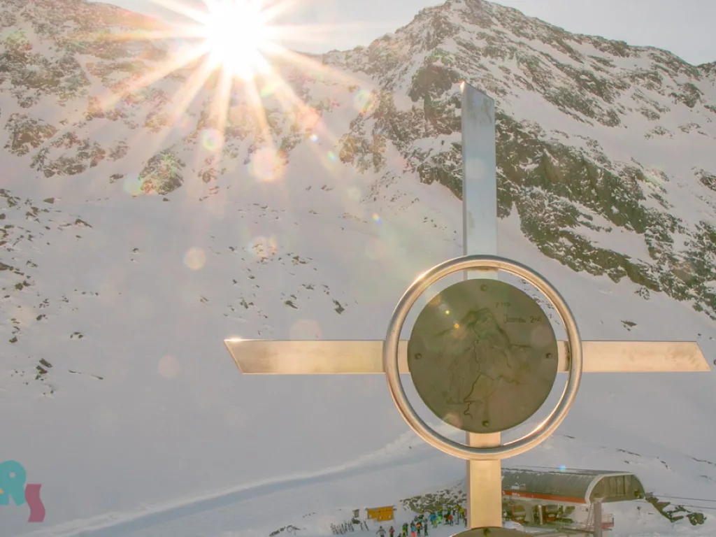 Gipfelkreuz vor der Sonne über den Bergen.